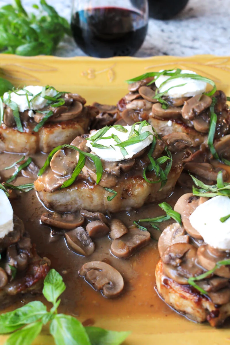 Mushroom and Goat Cheese Pork Chops are seared in a skillet and then finished in the oven.  The juicy pork chops are accompanied by an irresistible combination of red wine mushrooms, creamy goat cheese, and fresh basil.