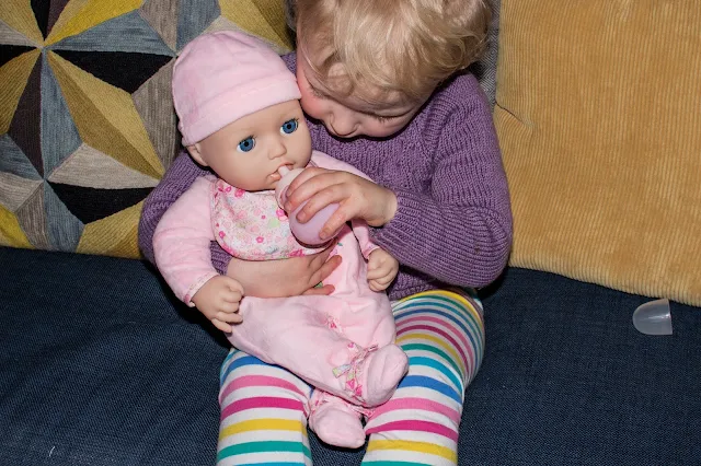 A toddler giving Baby Annabell her bottle