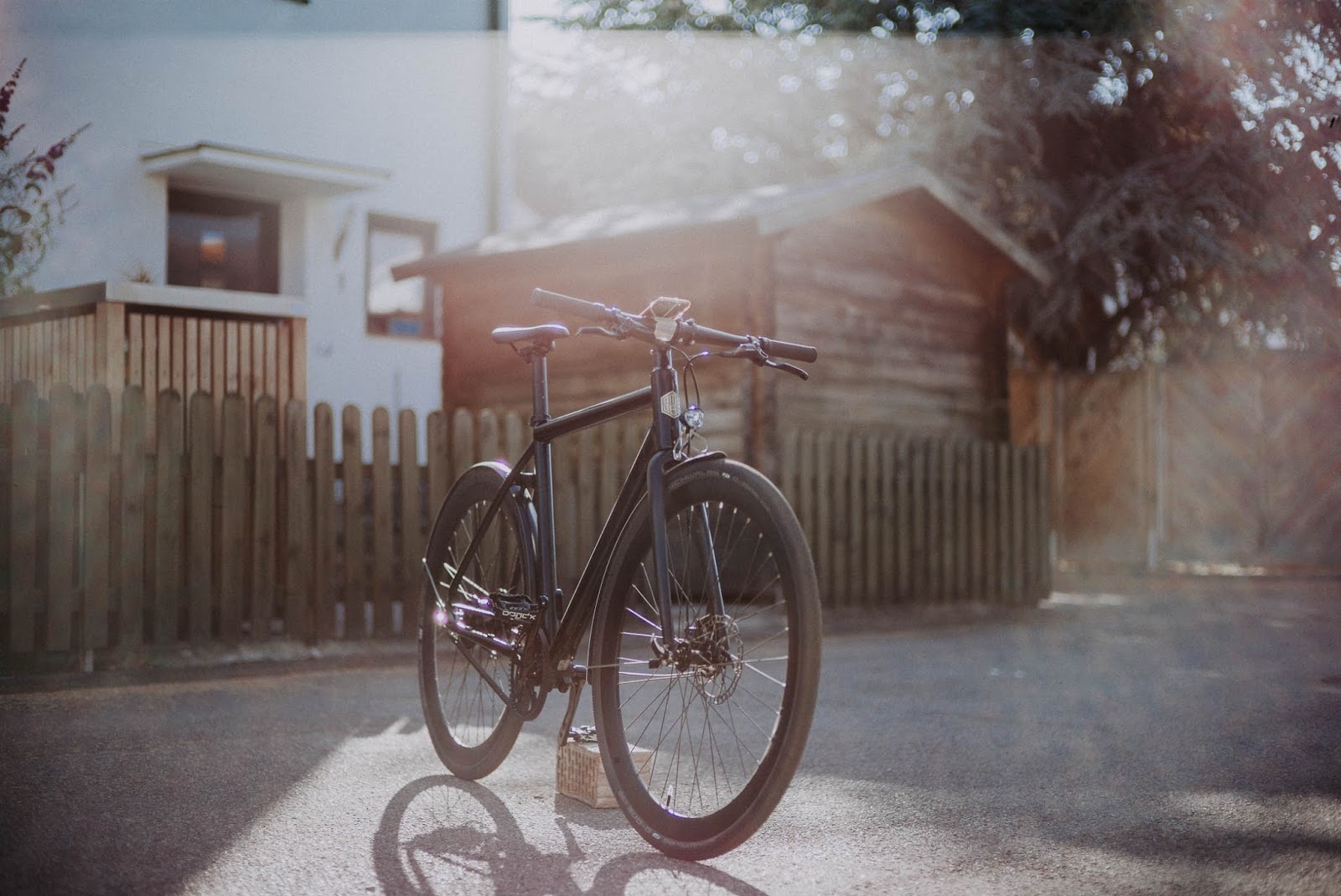 AMPLER HAWK E-Bike in Singlespeed Look und App-Konnektivität vor einem Zaun abgestellt