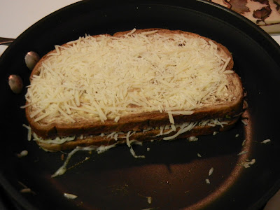 sandwich with parmesan cheese on the top of it in a frying pan 