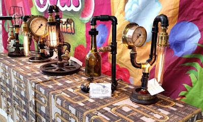 Lamps are made using old metal plumbing pipe, regulator gauges, brass fittings, parts of coloured glass bottles, and the incandescent lights have various shapes like long tubes or standard globes.