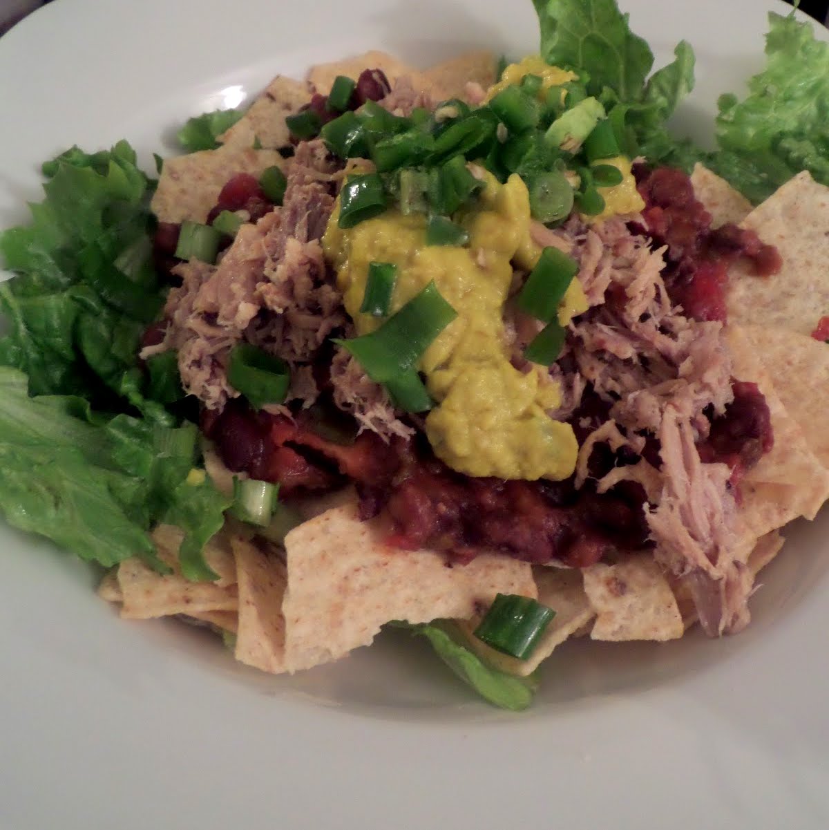 Pulled Pork Taco Salad:  A taco salad topped with spicy black beans, pulled pork, and avocado.