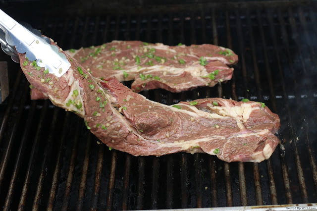 Marinated steak being placed on grill