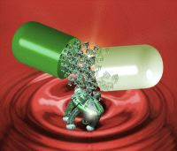 Imagem de uma capsula de remédio sendo aberta, e caindo seu conteúdo, algumas bolinhas verdes pequenas.