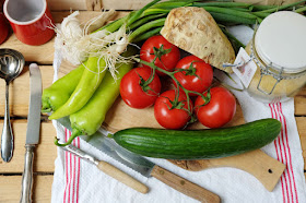Grüne Paprika, Toaten, Gurke, Sellerie, rote Tomaten auf einem Oliven-Holzbrett mit Messern