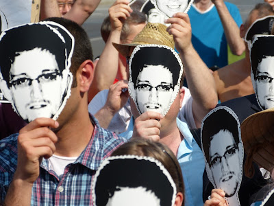 Protesters wear paper Snowden masks