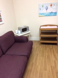 Parent and baby room with sofa, microwave and changing table