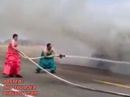 2 orang bomba berpakaian gaun memadamkan kebakaran