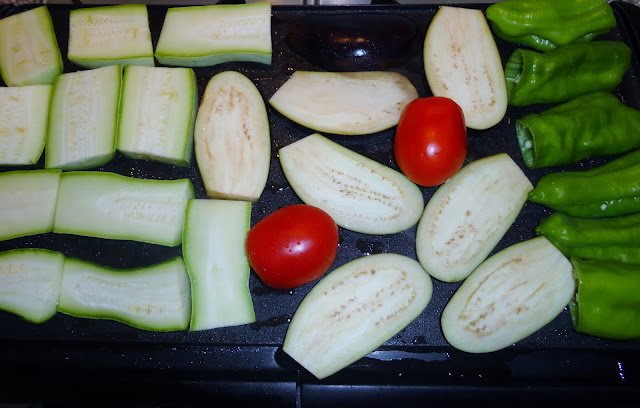 BERENJENAS, CALABACÍN, PIMIENTOS y TOMATES COLOCADOS SOBRE UNA PLANCHA PARA SER COCINADOS