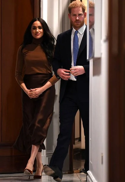 Meghan Markle wore Stella Mccartney double-breasted wool coat and Massimo Dutti brown satin midi skirt. Prince Harry