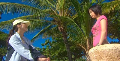 Mikami and Misaki talk with a backdrop of coconut trees.