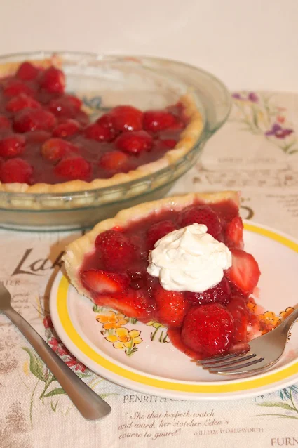 Slice of fresh strawberry pie topped with whipped cream.