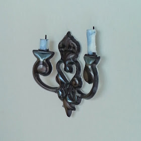 One-twelfth scale metal wall candle holder with white candles.