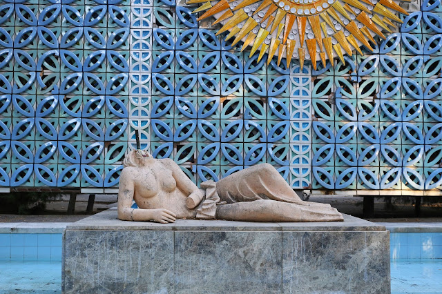 Estatua dañada en un monumento junto a otros elementos ornamentales.