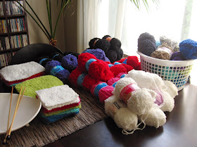 Dining table covered in balls of fluffy yarn and completed dolls house flokati rugs