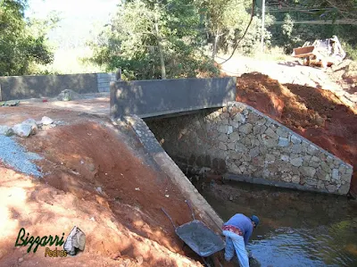 Construção do muro de pedra com pedra bruta para a base da construção da ponte de concreto na entrada da empresa em Atibaia-SP.