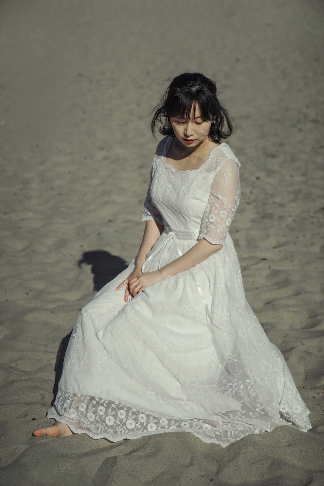ウエディングドレスを着て砂浜に座っている女性