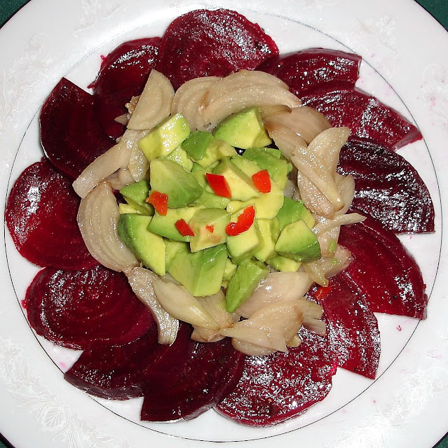 PORTIONS: 4 INGREDIENTS 2 lb. beets, cooked, peeled, cut in rounds 3 medium size pickled onions, sliced 2 avocados, peeled, diced 4 Tbsp. olive oil 2 Tbsp. red wine vinegar ¾ tsp. salt ⅛ tsp. ground pepper 1 Tbsp. Lemon juice Red pepper for decoration PREPARATION Make vinaigrette by beating the olive oil with the vinegar, salt and pepper. Use half of the vinaigrette to mix with the beets and, the other half mix with the onions. Mix the avocados with the lemon juice. Arrange the beets and onions in a circle and place the avocados in the center.  Add chopped red pepper on top for decoration.