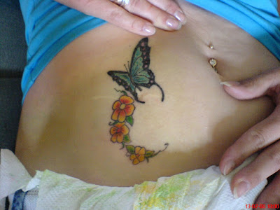 Tatuaje mariposa y flores en el abdomen