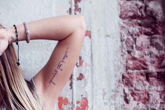 vemos a una modelo joven con un tatuaje en el interior del biceps