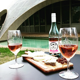 Two glasses of rose, with the bottle they came from (and a cheese board) on a table in front of The Shine Dome.