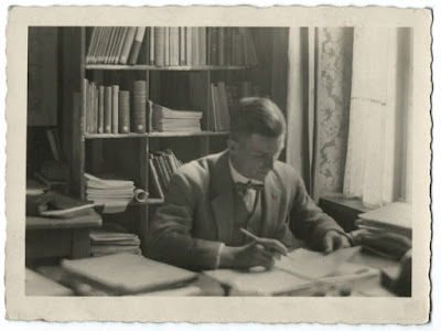 Altes Schwarz-weiß-Bild mit Mann am Schreibtisch vor einem Regal