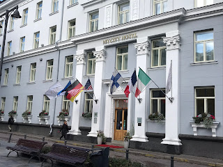 Fasaden til en eldre bygning med ulike flagg ved inngangen.