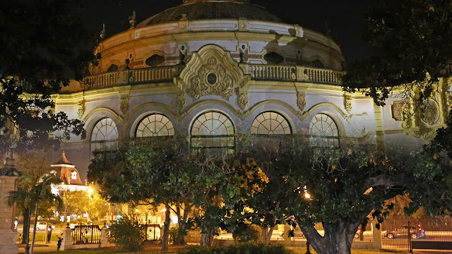 Vista de la fachada del Casino de exposición de Sevilla iluminado por la noche, desde la calle.