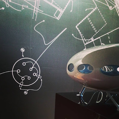 Model of a Futuro House in front of a wall of sketches of its design.