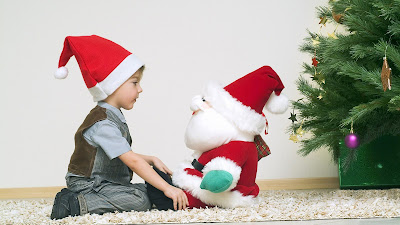 Un niño platica con Santa Claus junto al árbol de Navidad