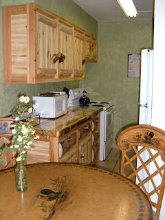 Kitchen with beautiful log cabinets, tile floors, and faux green walls.  Dinning table with faux painting of a rooster