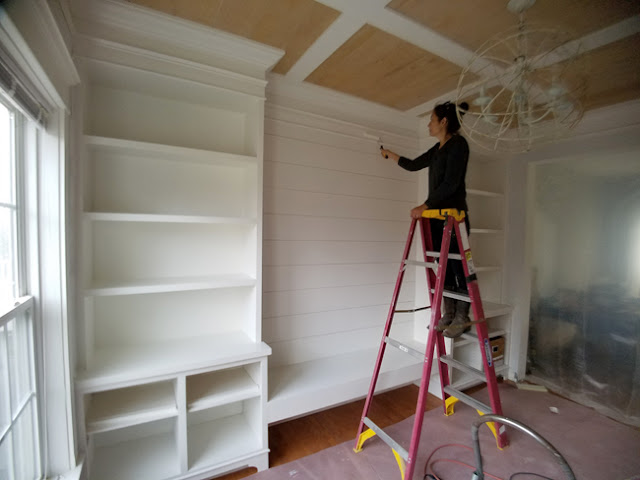 Cristina Garay on ladder painting the planked wall