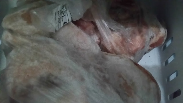 Two frozen meat packs in plastic wrapper inside freezer