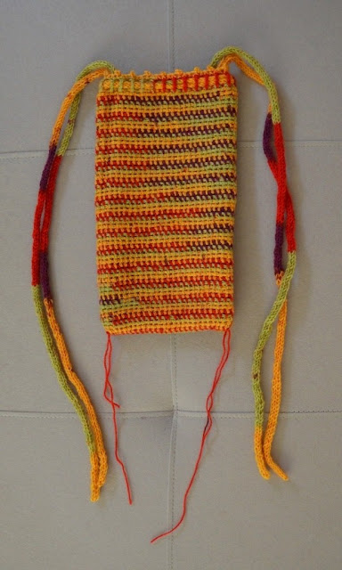 Crocheted bag laid flat with a section of red yarn marking each borrom corner.