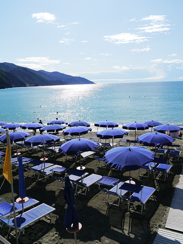 Open umbrellas on the beach on a sunny day in Monterosso al Mare, Cinque Terre, Italy