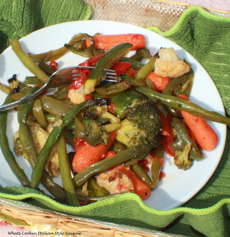 this is a photo of roasted vegetables. This is an easy recipe showing how to make roasted vegetables. After baked they are in a colorful basket in a white plate and green towel to look pretty on the table. These roasted vegetables and a healthy addition to any Keto Diet or for those watching their weight and caloric intake