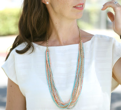 Andrea wearing a white t-shirt and the completed multi-colored seed bead necklace