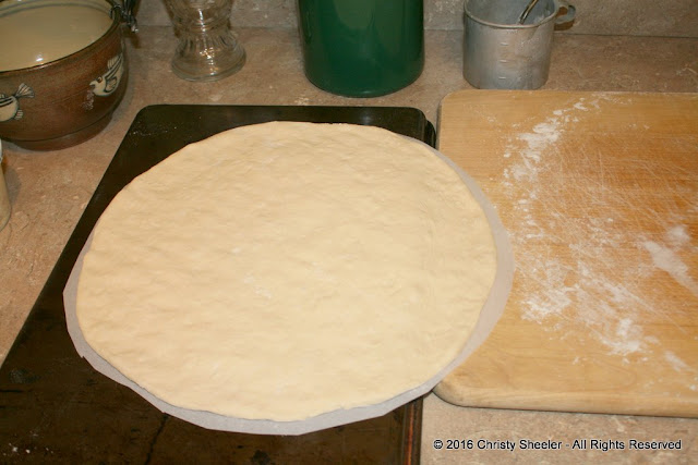 The stretched dough is set on the parchment paper. 