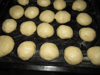 Shaped bread rolls lined on a brown baking tray ready for the oven
