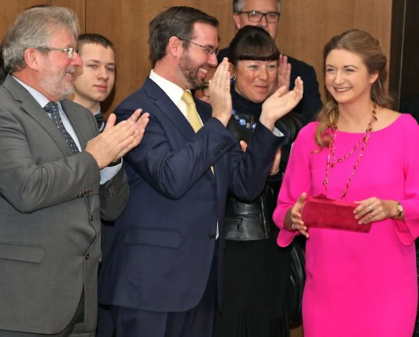 Princess Stephanie wore a fuchsia color Prada Dress, Prada Bordeaux Coloured suede shoes, Prada Bordeaux Coloured clutch bag and Colored stone ruby necklace and ruby ring