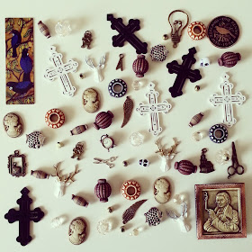 Selection of miniature pictures, vases, crosses and charms laid out on a tabletop.