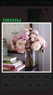  на столе в вазе стоят цветы пионы и лежат книги
