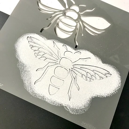 Bee stencil with white paint on a chalkboard