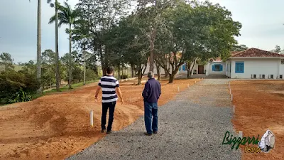 Acertando a terra para a execução da rua com o calçamento com pedras tipo de piso com pedrisco compactado com as guias de pedra, com pedra folheta, em rua da entrada da sede da fazenda em Atibaia-SP e a execução do paisagismo.