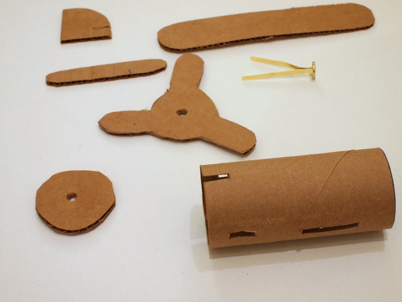 cut out cardboard pieces to make toilet roll airplane