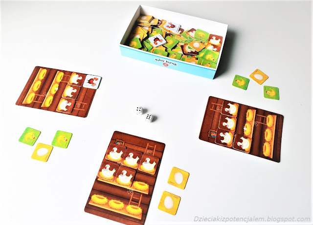 na zdjęciu pudełko z elementami gry oraz trzy plansze graczy