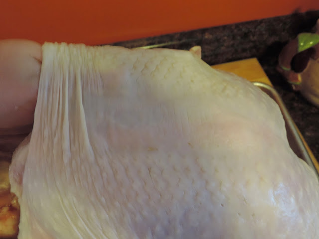 The butter being placed under the skin of the turkey.