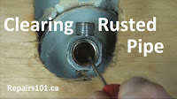 using a screwdriver to remove rust from pipe