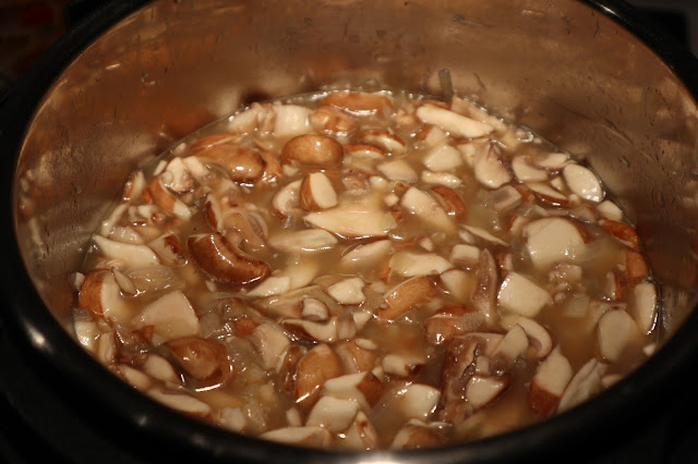 Mushrooms floating inside a pot filled with chicken stock.