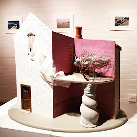 One-twelfth scale model of a two-story building on display in a gallery.